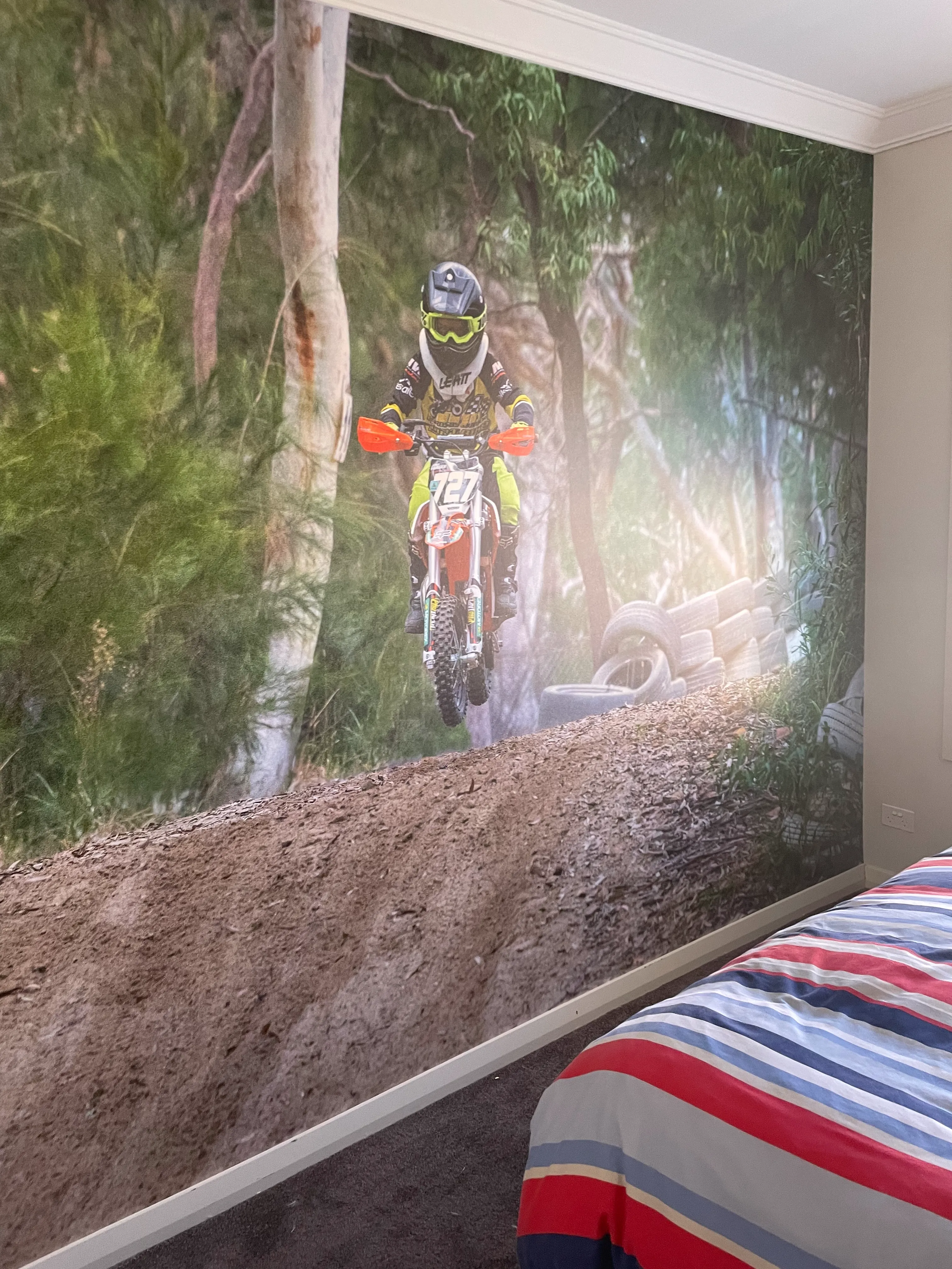 Photo of customer's sporty motocross son on custom printed wallpaper in kid's room