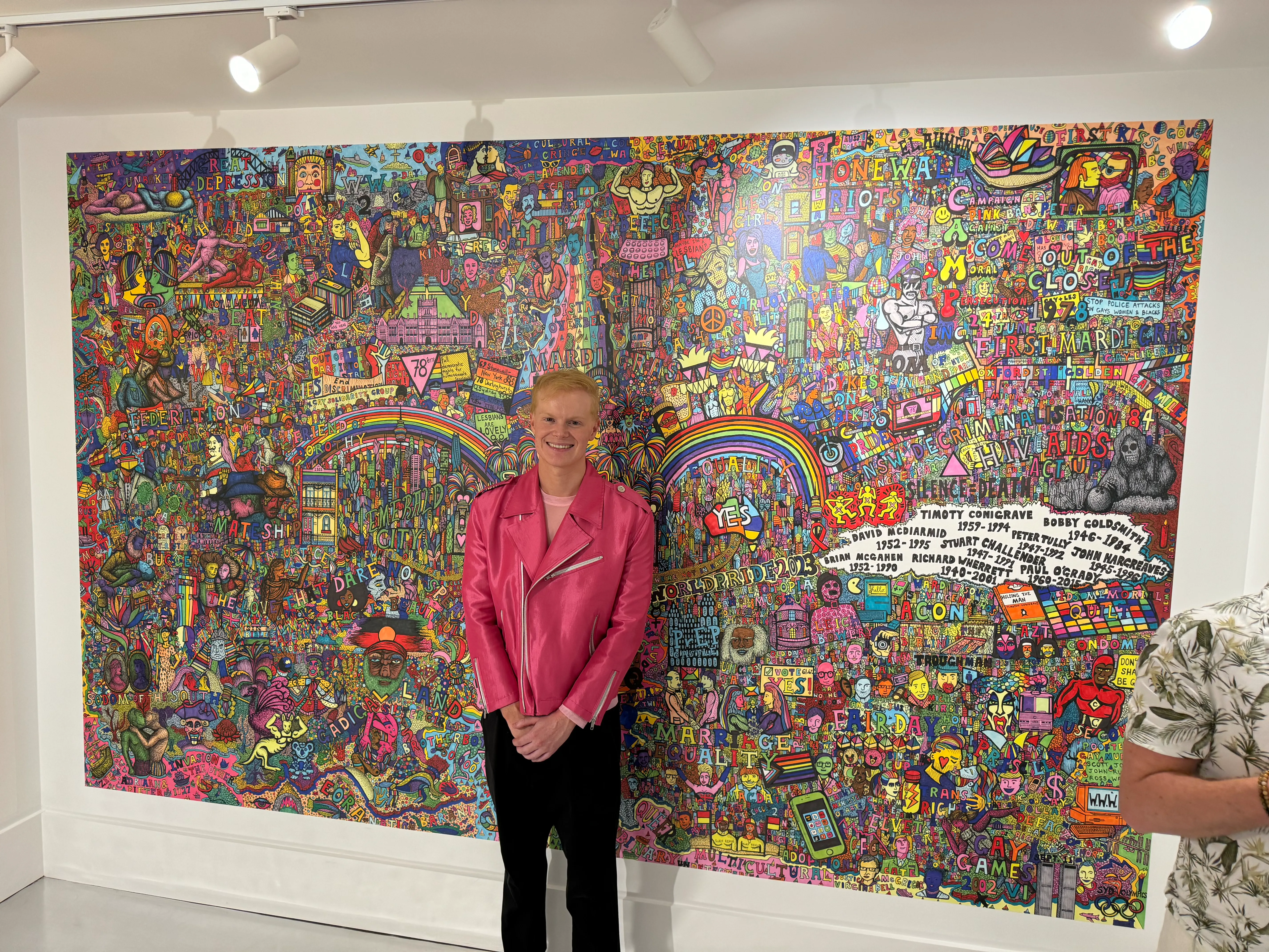 Artist Jeremy Smith in front of his artwork The History of Queer Sydney at Qtopia